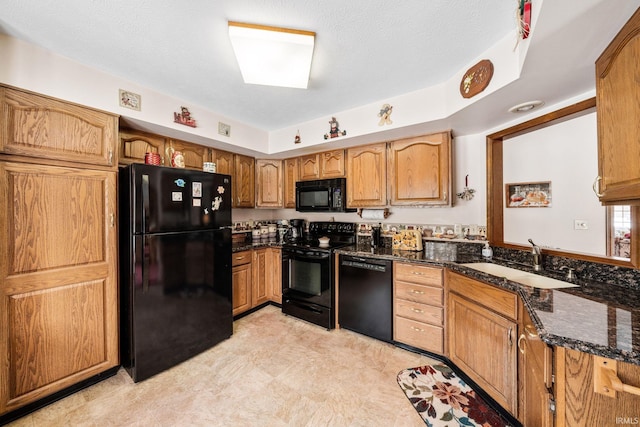 kitchen with brown cabinets, dark stone countertops, a textured ceiling, black appliances, and a sink