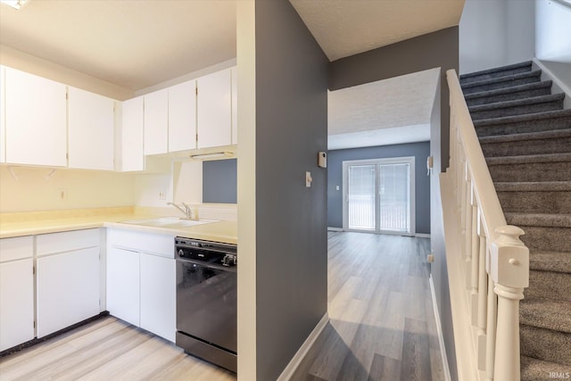 kitchen featuring light wood-type flooring, black dishwasher, white cabinetry, and a sink