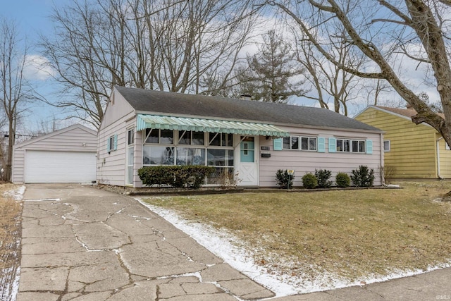 ranch-style home featuring an outbuilding, a detached garage, and a front lawn