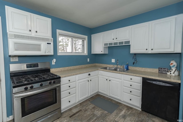 kitchen with black dishwasher, visible vents, white microwave, gas stove, and a sink