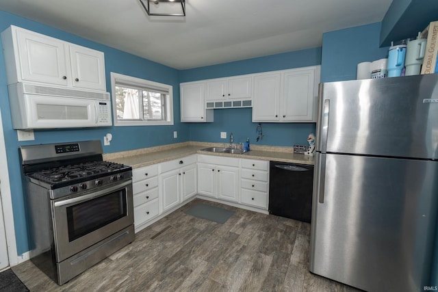 kitchen with dark wood-style flooring, a sink, white cabinetry, light countertops, and appliances with stainless steel finishes