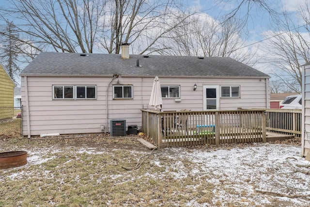 snow covered back of property featuring a shingled roof, fence, central AC unit, and a wooden deck