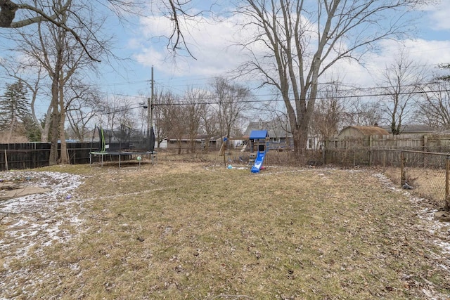 view of yard with a trampoline, a playground, and a fenced backyard