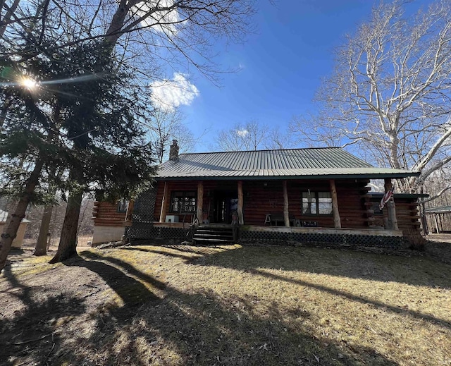 back of property with covered porch, metal roof, a chimney, and log siding