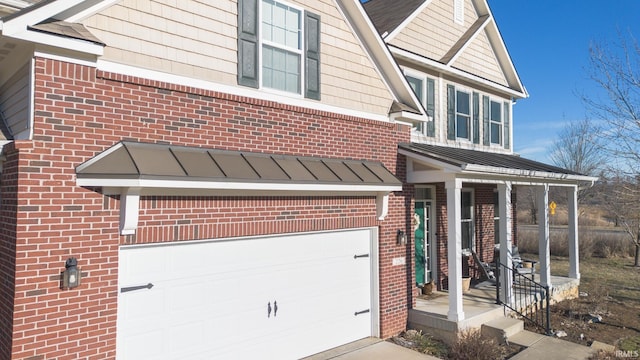 view of front of property featuring a garage, brick siding, and a standing seam roof