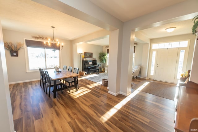 dining space featuring an inviting chandelier, baseboards, and wood finished floors