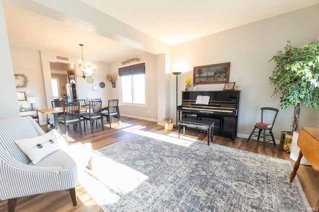 living area featuring an inviting chandelier, baseboards, and wood finished floors