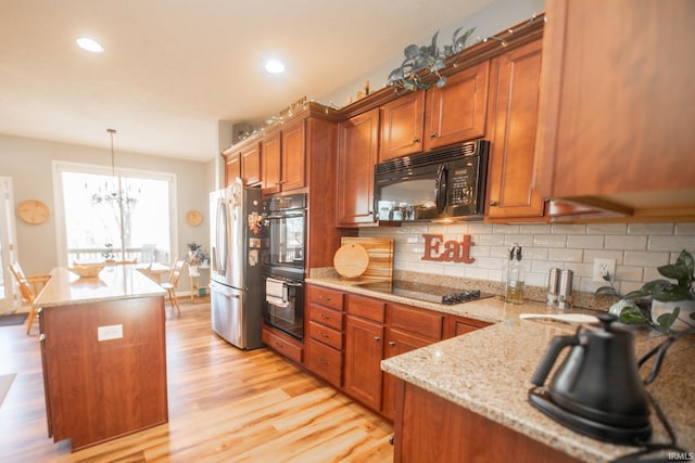 kitchen featuring black appliances, brown cabinets, backsplash, and light wood finished floors