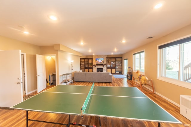 rec room featuring recessed lighting, a fireplace, wood finished floors, baseboards, and radiator