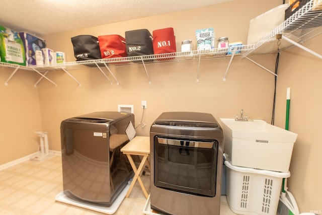 clothes washing area featuring a textured ceiling, laundry area, baseboards, independent washer and dryer, and tile patterned floors