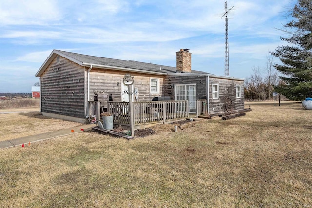 back of house with a chimney and a lawn