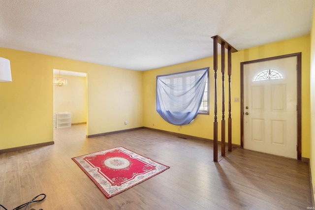 entrance foyer featuring a textured ceiling, baseboards, and wood finished floors