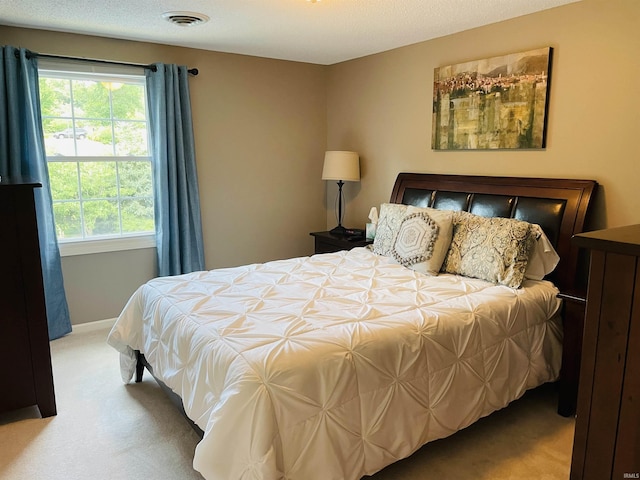 carpeted bedroom with visible vents, a textured ceiling, and baseboards