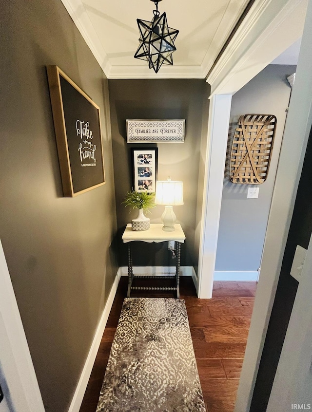 hallway with ornamental molding, baseboards, and wood finished floors