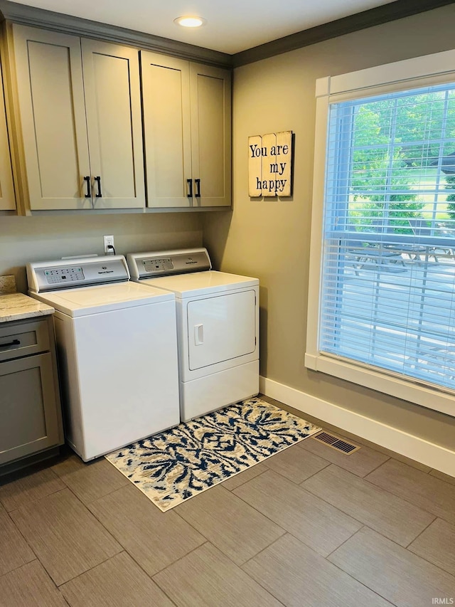 laundry area with wood finish floors, visible vents, baseboards, independent washer and dryer, and cabinet space