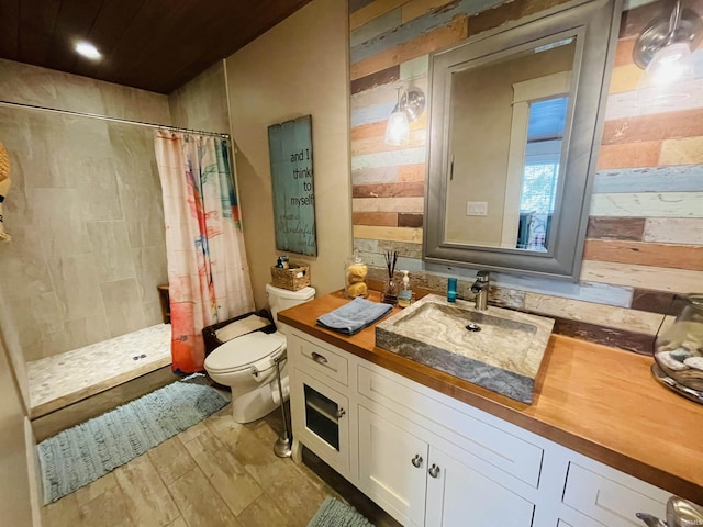 bathroom with toilet, wooden walls, tiled shower, and vanity