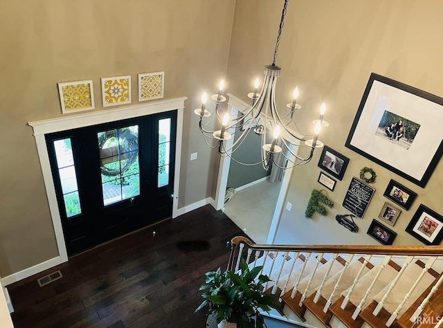 entrance foyer featuring baseboards, visible vents, dark wood finished floors, a towering ceiling, and stairway