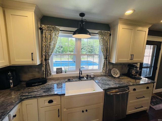 kitchen with stainless steel dishwasher, backsplash, a sink, and white cabinetry