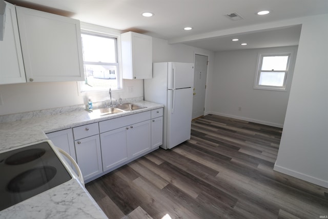 kitchen with dark wood-type flooring, freestanding refrigerator, white cabinetry, a sink, and range