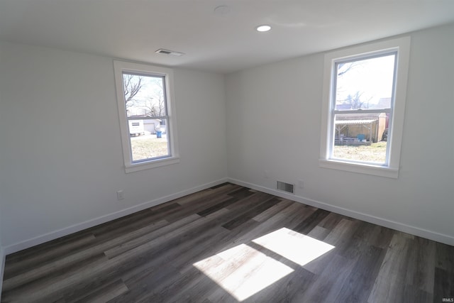 unfurnished room with dark wood-style floors, visible vents, and baseboards