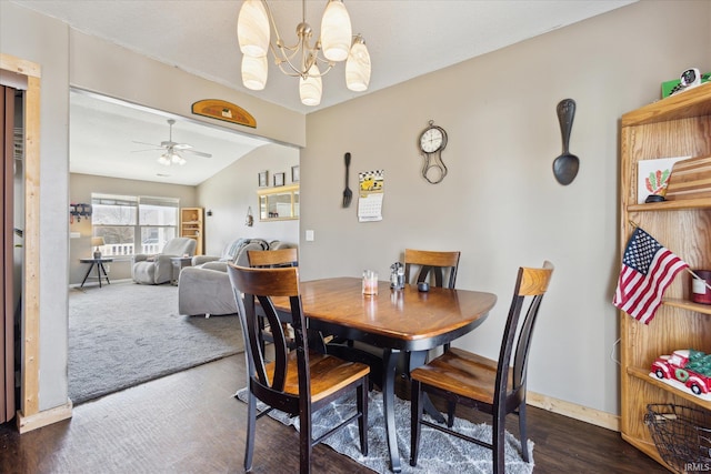 dining room with baseboards, vaulted ceiling, dark wood-type flooring, and ceiling fan with notable chandelier