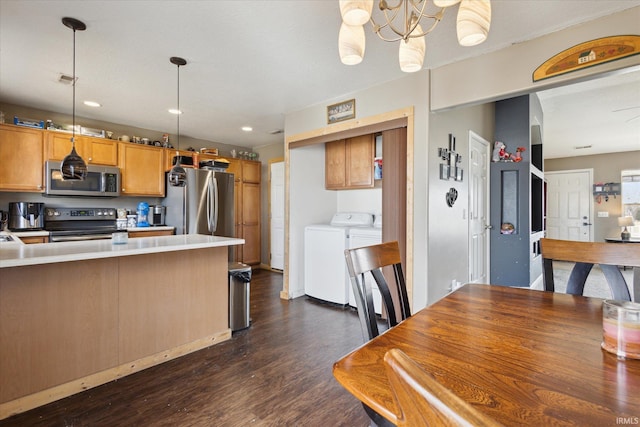 kitchen with stainless steel appliances, light countertops, hanging light fixtures, dark wood-type flooring, and separate washer and dryer