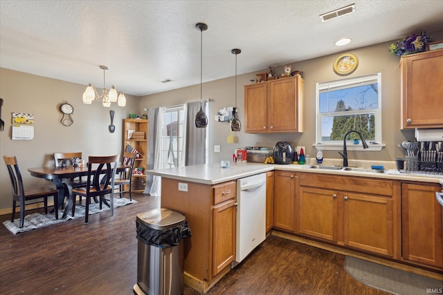 kitchen featuring light countertops, white dishwasher, a sink, and a peninsula