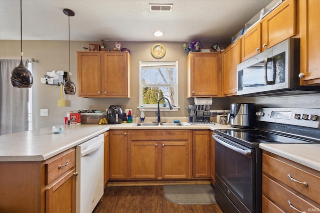 kitchen featuring dishwasher, stainless steel microwave, a peninsula, a sink, and range with electric stovetop