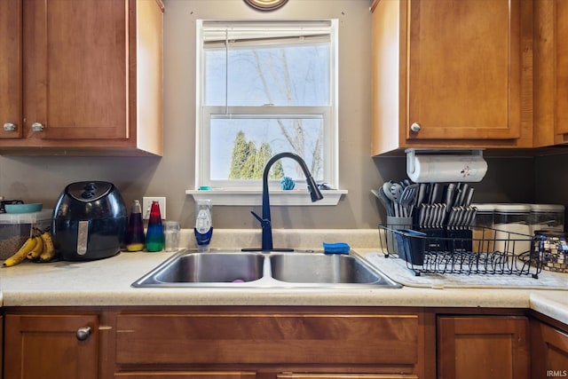 kitchen featuring brown cabinets, light countertops, and a sink