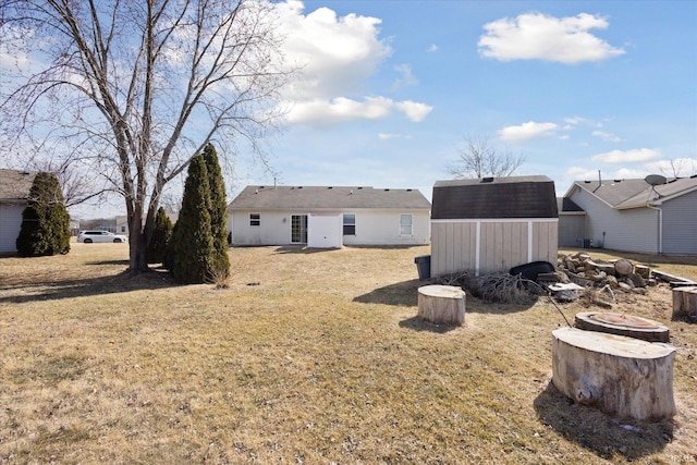 rear view of property featuring an outdoor structure, a storage shed, and a lawn