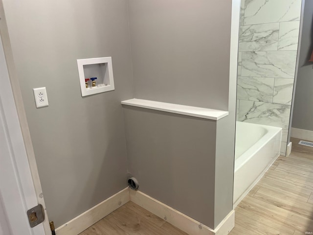 washroom featuring hookup for an electric dryer, hookup for a washing machine, light wood-style flooring, and baseboards