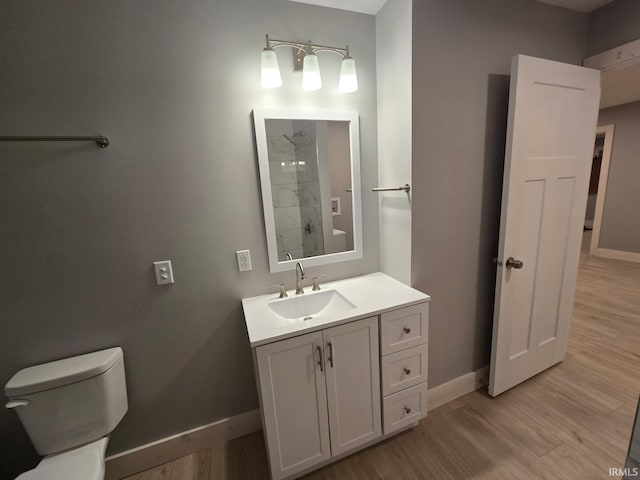 full bathroom featuring toilet, wood finished floors, vanity, baseboards, and walk in shower