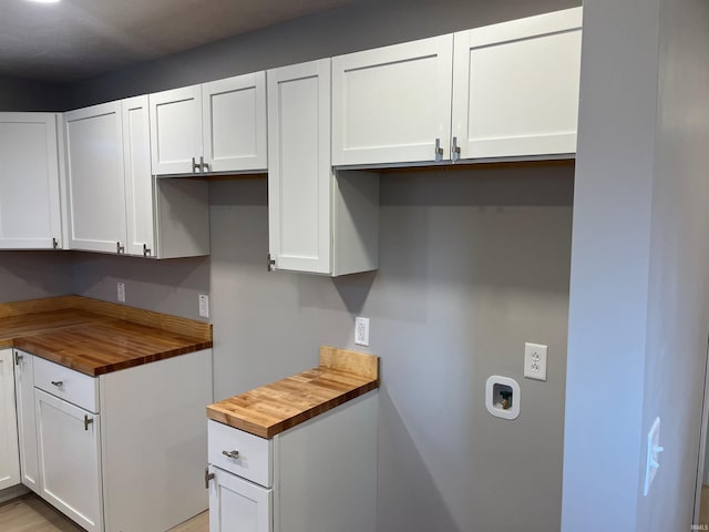 kitchen with wooden counters and white cabinetry