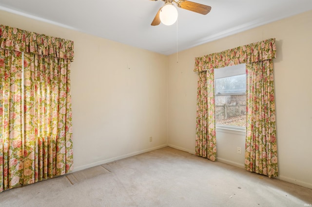 carpeted empty room featuring baseboards and a ceiling fan