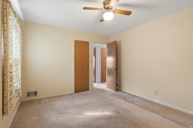 carpeted spare room featuring baseboards, visible vents, and ceiling fan