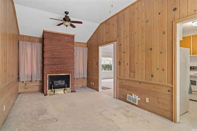 unfurnished living room with carpet floors, ceiling fan, wooden walls, and visible vents