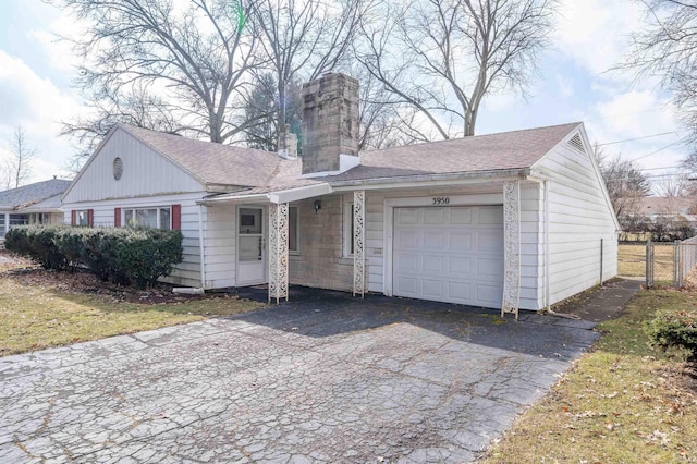 view of front facade featuring a garage, roof with shingles, a chimney, and fence