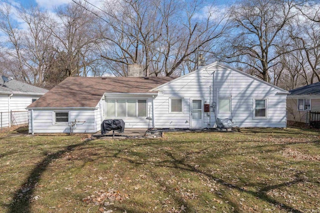 back of house featuring a lawn, a chimney, and fence