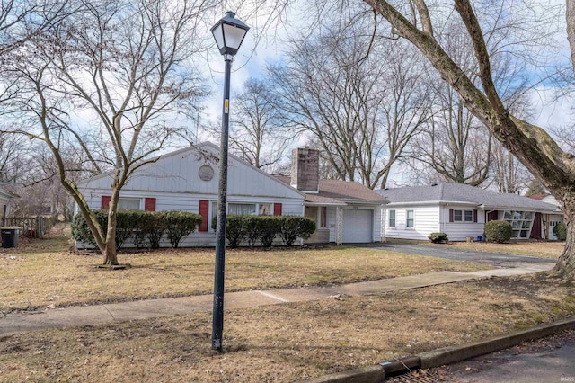 single story home with a garage, a chimney, a front lawn, and aphalt driveway