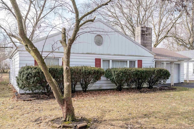 view of front of house with driveway, a chimney, and an attached garage