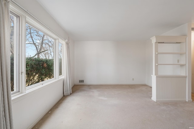 spare room featuring light colored carpet and visible vents