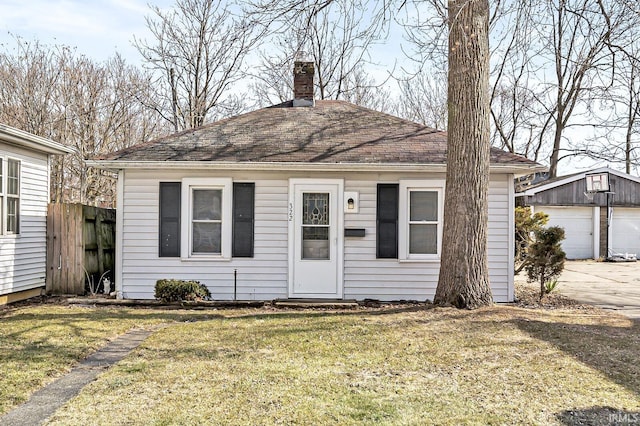 view of front of home with an outbuilding, a chimney, a front yard, and fence