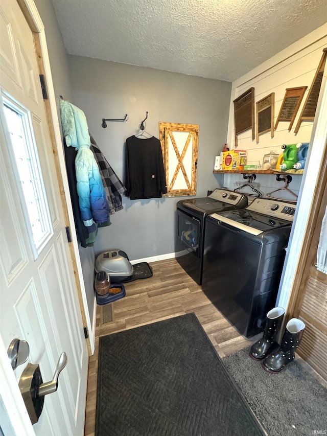 laundry area featuring laundry area, a textured ceiling, washer and clothes dryer, and wood finished floors