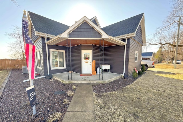 view of front of property featuring a shingled roof, fence, and central AC unit