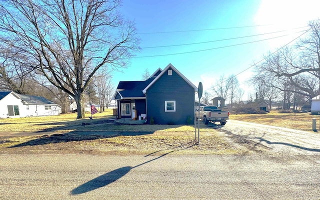 view of side of home featuring dirt driveway and a lawn