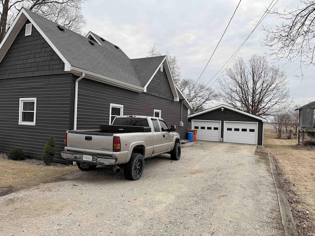 view of home's exterior featuring roof with shingles, a detached garage, and an outdoor structure