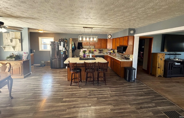 kitchen with dark wood-style floors, a center island, light countertops, and black appliances