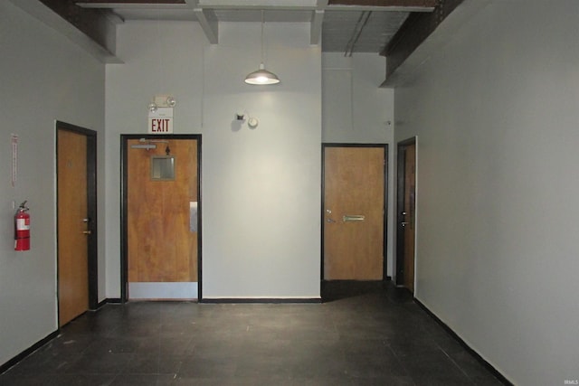 hall featuring a towering ceiling and baseboards