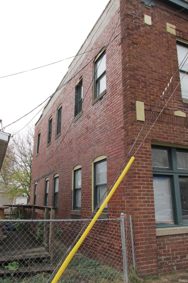 view of side of property with brick siding and fence