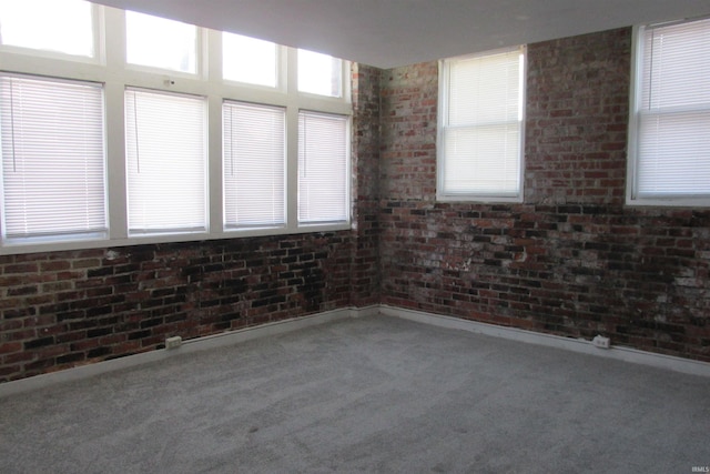 carpeted empty room featuring brick wall